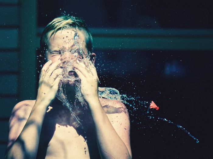 Boy getting hit in the face with a water balloon