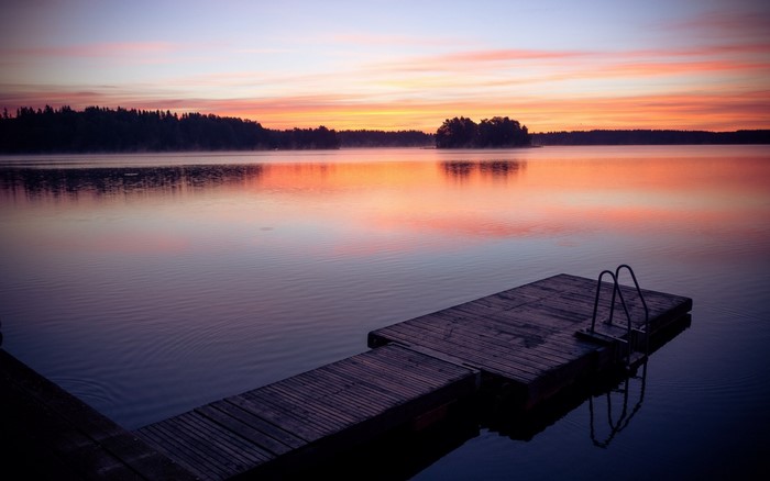 Wooden pier on a lake at sunset with colorful sky reflection