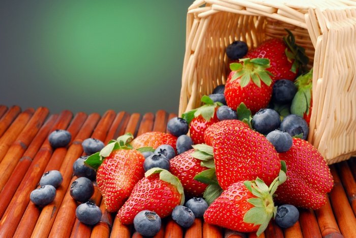 Strawberries and blueberries spilling from a basket