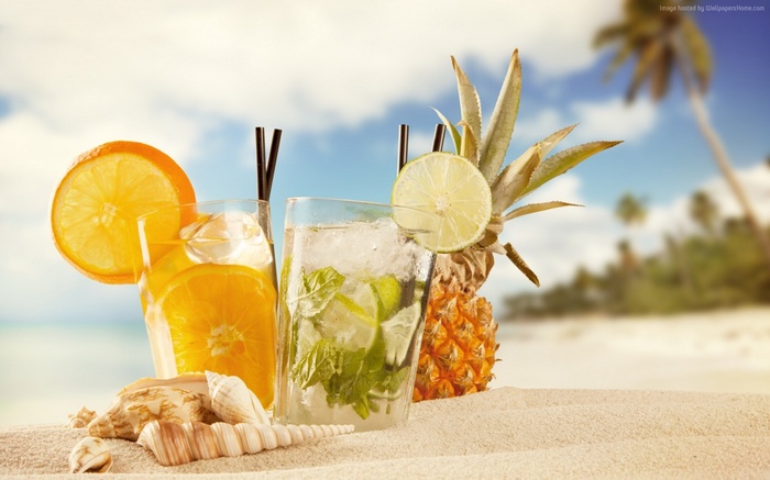 Tropical cocktails on a sandy beach with pineapple and shells