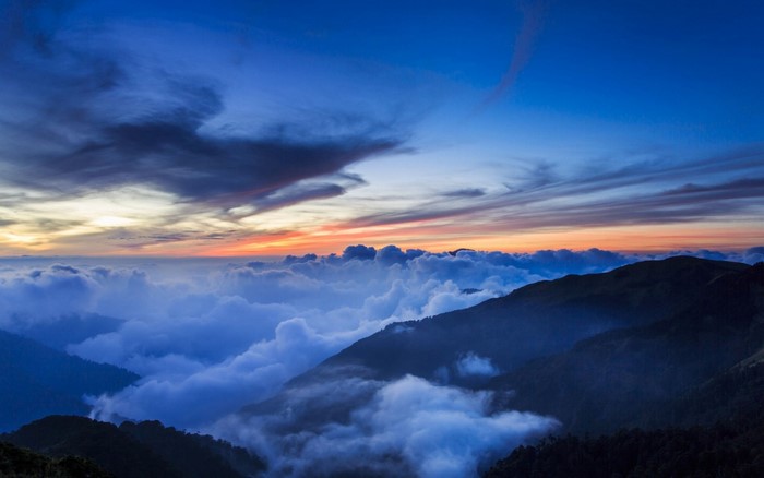 Mountain range above clouds at sunset