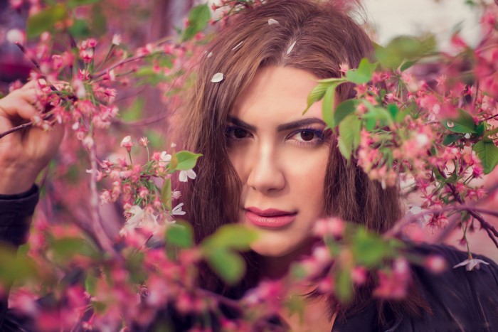 Woman posing among pink cherry blossoms