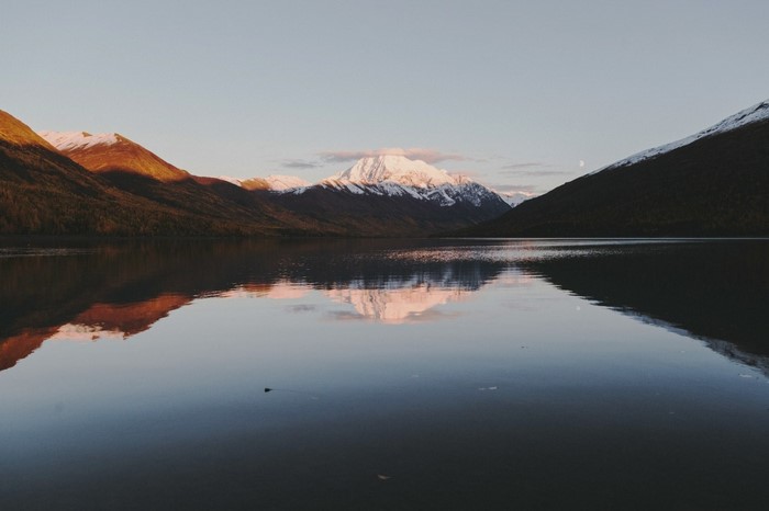 Snow-capped mountains reflected in a calm lake at sunrise