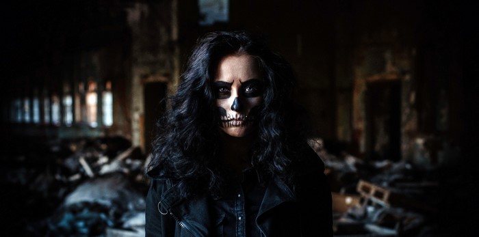 Woman with skull face paint in dark abandoned building