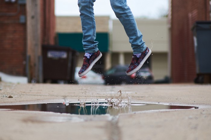 Person jumping through a puddle