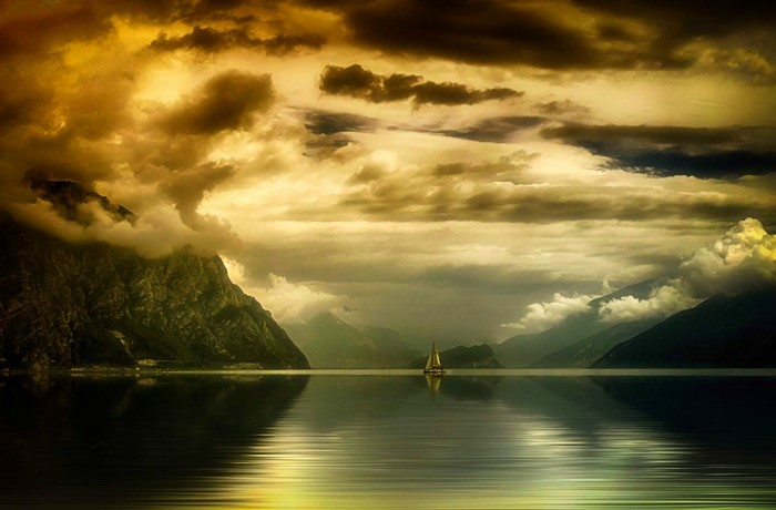 Sailboat on a lake with mountains and dramatic clouds