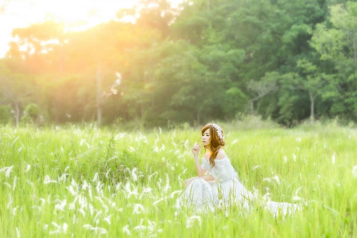 Woman in white dress sitting in a grassy field