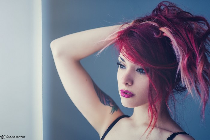 Thoughtful Woman with Vibrant Red and Pink Hair