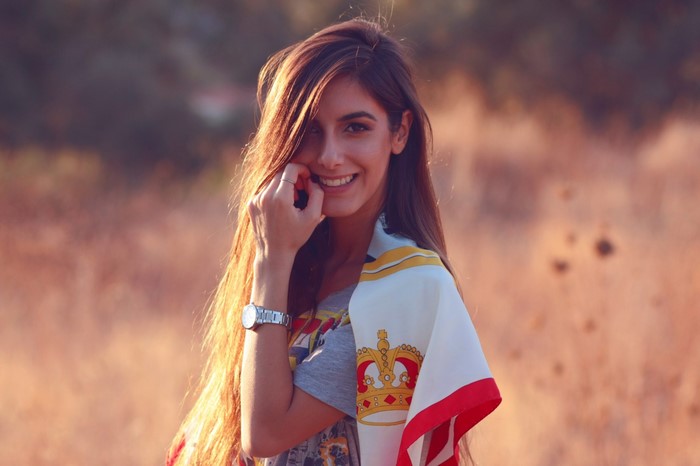 Woman with long brown hair smiling outdoors