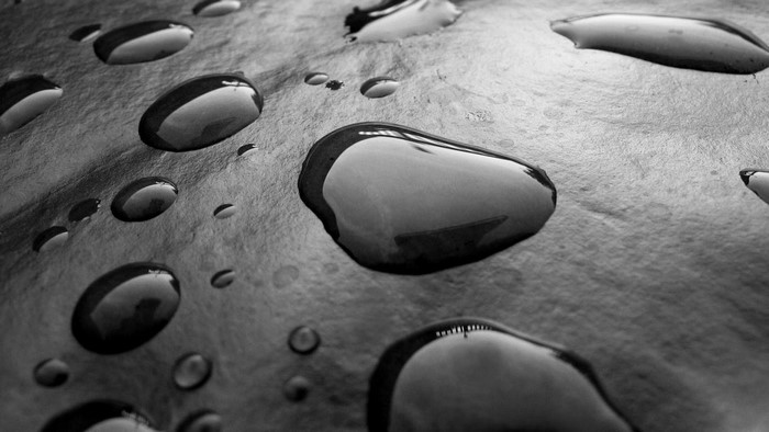 Monochrome close-up of water drops on a textured surface
