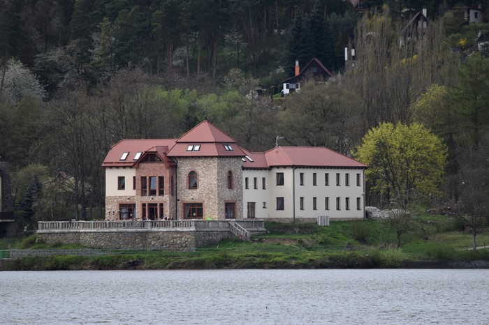 Large house on the shore of a lake with a forest in the background