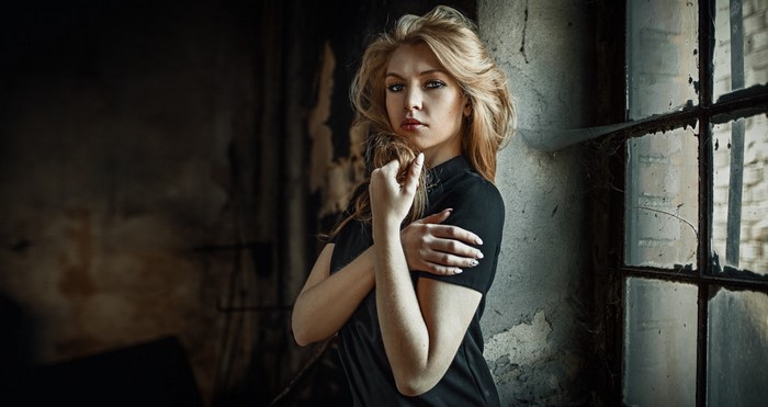 Woman posing in abandoned building by window