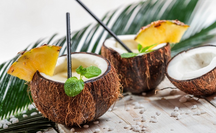 Two coconuts filled with pina colada cocktails and pineapple slices