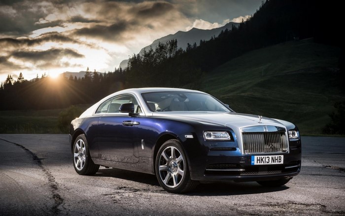 Rolls Royce Wraith parked on a road with mountains at sunset