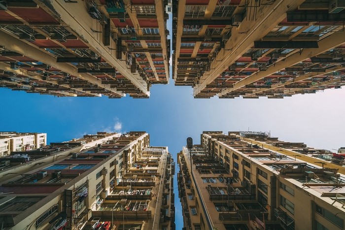 Looking up at dense apartment buildings against a blue sky