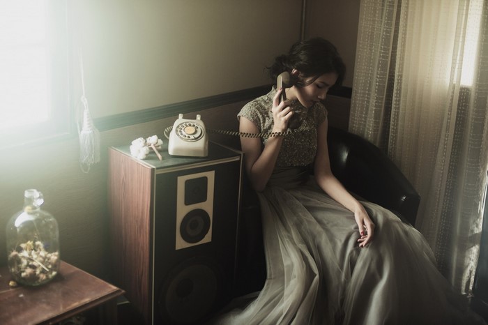 Woman in a dress talking on a vintage telephone