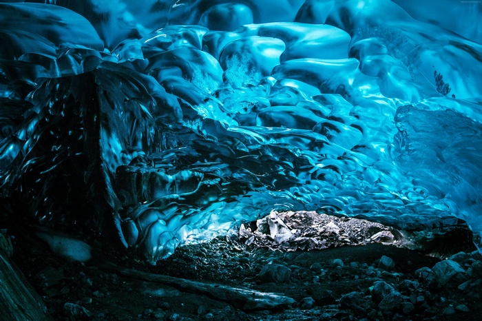 Inside a blue ice cave with water and rocks