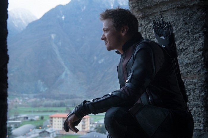 Hawkeye from The Avengers crouches by a stone wall