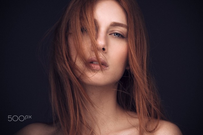 Redhead woman with hair in face, blue eyes, portrait