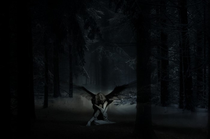 Fallen angel in a dark, snowy forest at night