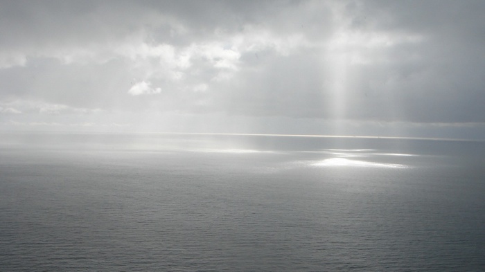 Sunlight beams through clouds onto a calm ocean