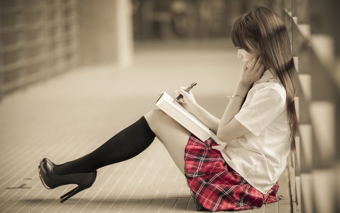 Young Woman Sitting and Writing in Red Plaid Skirt
