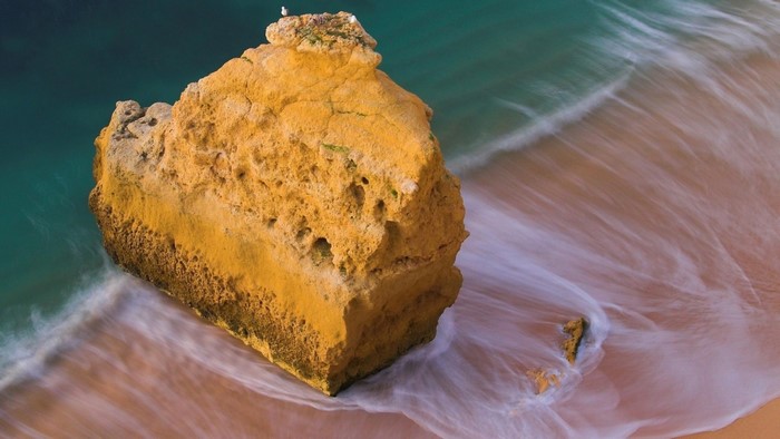 Yellow rock formation with waves on a beach