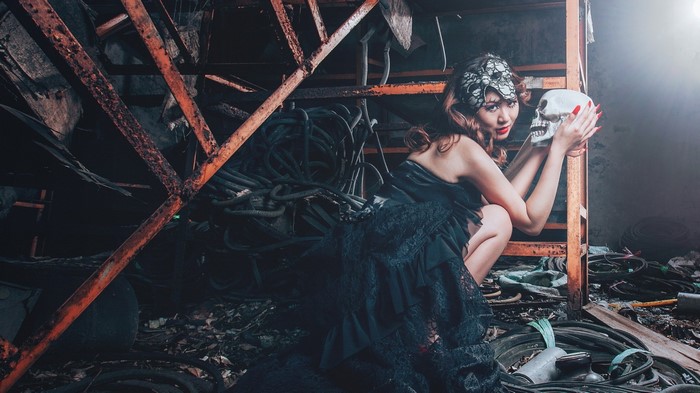 Asian woman in black dress holding a skull
