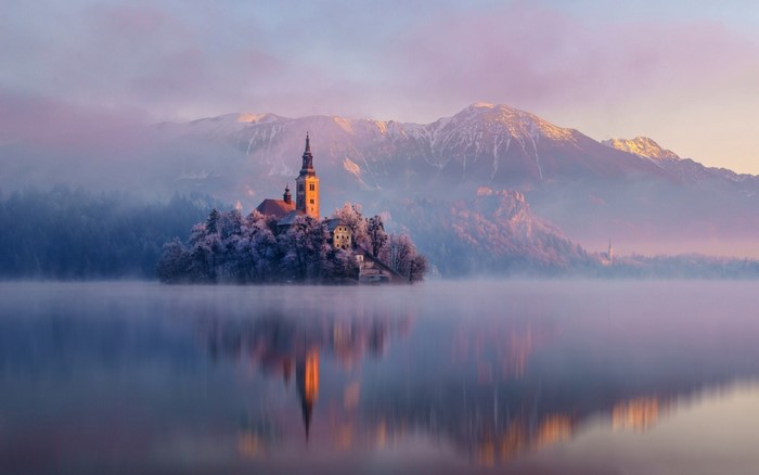 Church on island in Lake Bled at sunrise with mountains