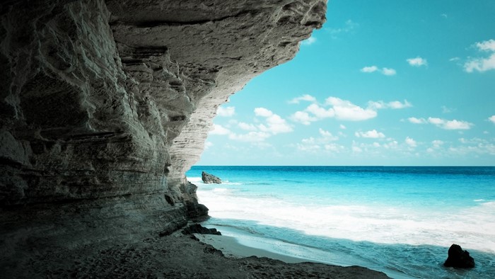 Cave opening overlooking a tropical beach and ocean