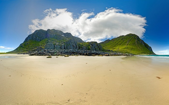 Sandy beach with green mountains and blue sky
