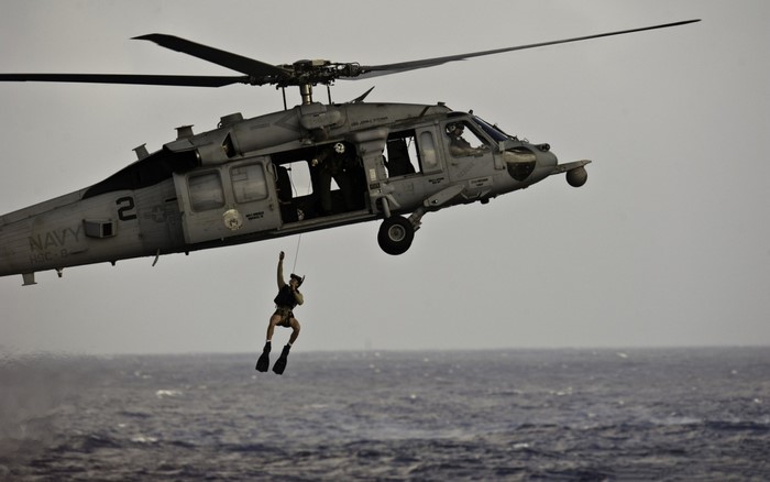 Navy helicopter rescuing a person over the ocean
