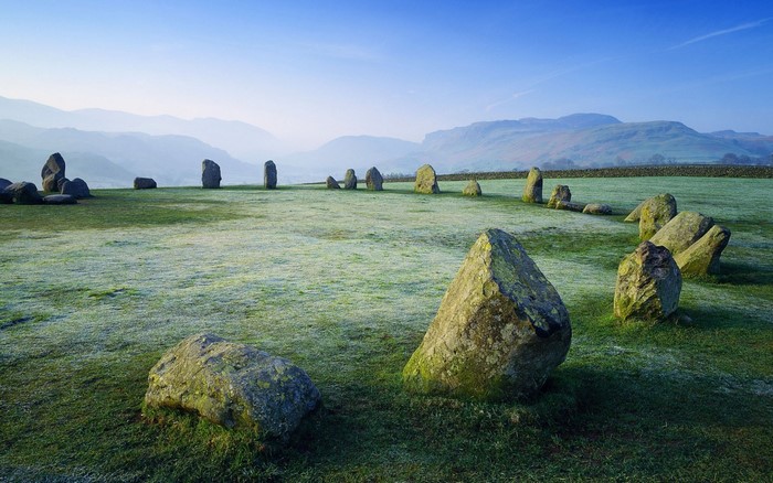 Stone circle on a frosty grassy field with mountains in the background