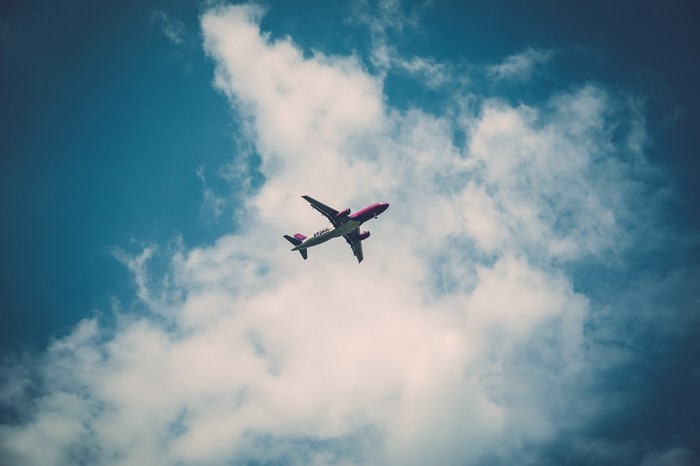 Airplane flying through clouds in a blue sky