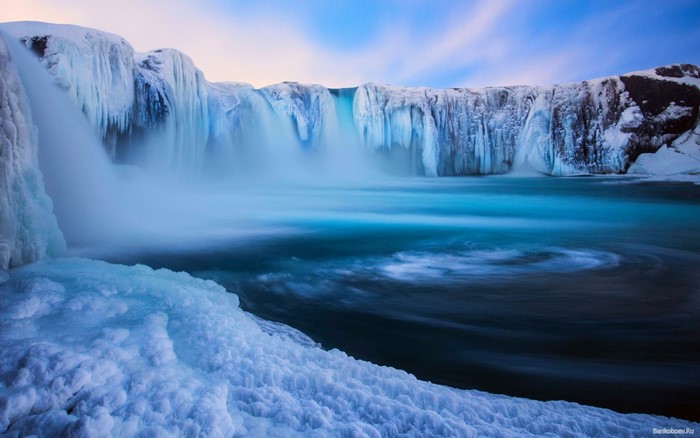 Frozen waterfall with icy cliffs and turquoise water