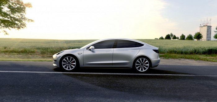 Silver Tesla Model 3 driving on a road near a field