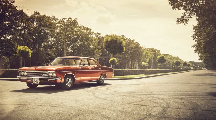 Red vintage Chevrolet Impala parked on a road