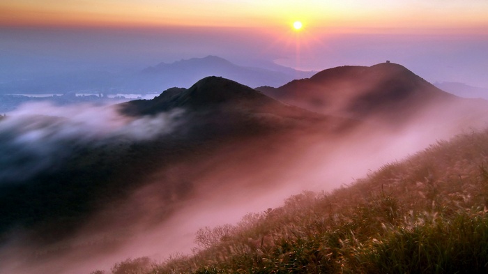 Misty mountains at sunrise with golden sun