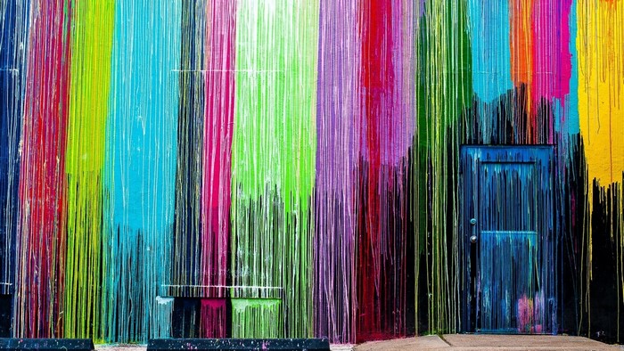 Colorful dripping paint mural with a blue door