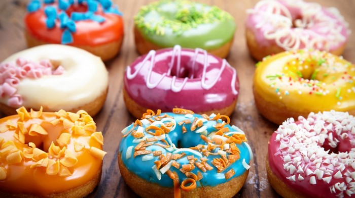 Assortment of colorful frosted donuts with toppings