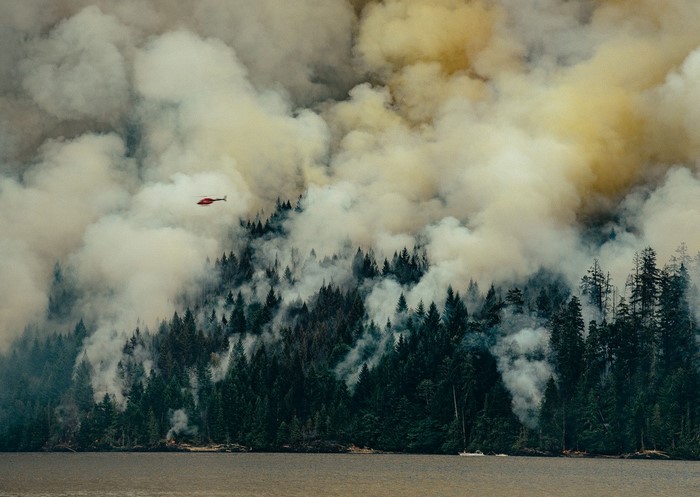 Helicopter battles wildfire over forest and water