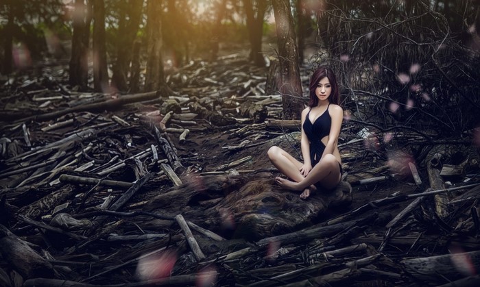 Woman in Black Outfit Sitting in a Sunlit Forest
