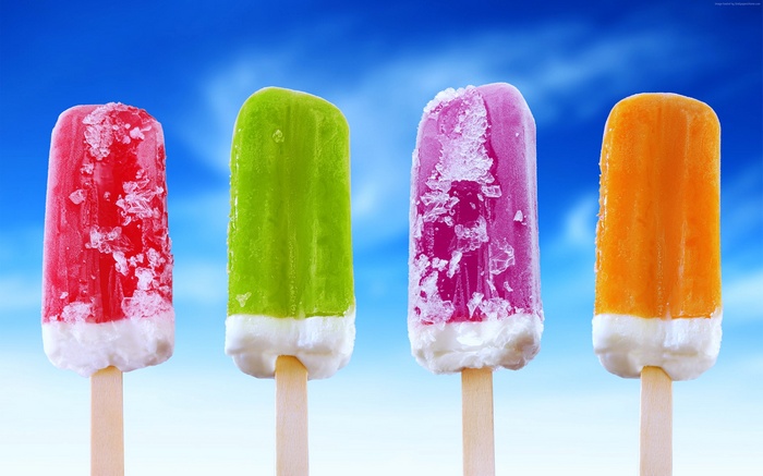 Four colorful popsicles on sticks against a blue sky
