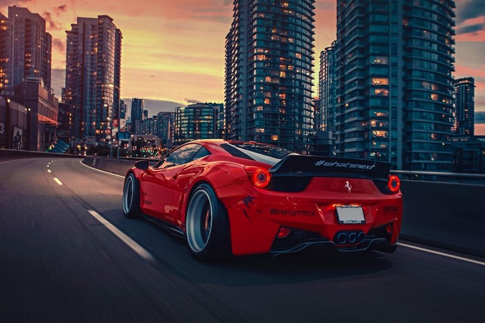 Red Ferrari 458 Italia driving in city at sunset