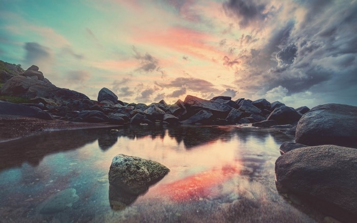 Rocky coast with calm water reflecting sunset sky