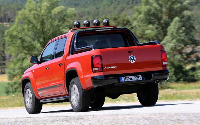 Orange Volkswagen Amarok pickup truck driving on a road