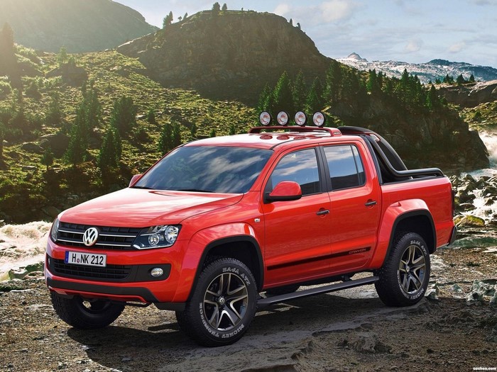 Red Volkswagen Amarok pickup truck in a mountainous landscape