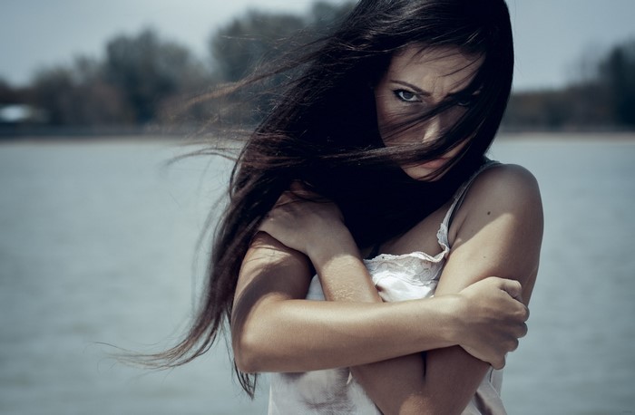 Woman in White Dress Embracing Herself by Water