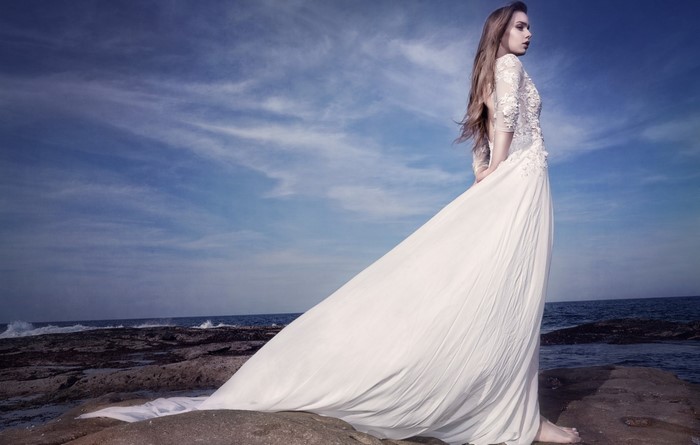 Woman in a white wedding dress on a rocky shore