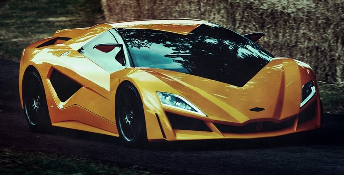 Orange supercar driving on a dirt road with hay bales
